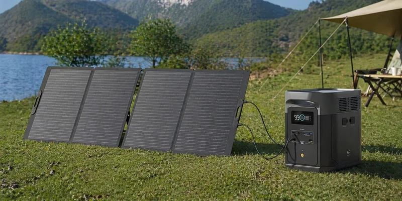 EcoFlow Delta 2 Max portable power station connected to a large solar panel at a lakeside campsite.